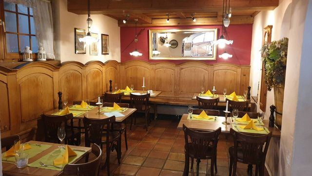 Gastraum der Pizzeria Grottino mit roter Wand und gedeckten Tischen