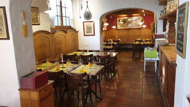 Langer Gastraum der Pizzeria Grottino mit Holzdecke und Tischreihen