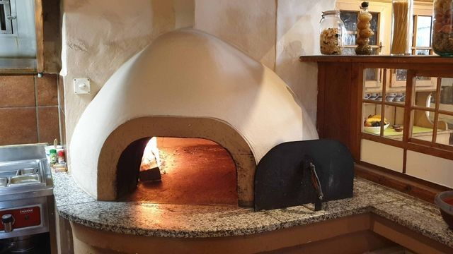 Gemauerter Holzofen mit weisser Kuppel in der Pizzeria Grottino