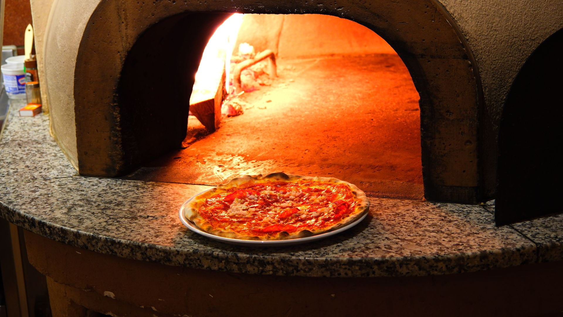 Pizza mit Tomaten und Basilikum vor dem glühenden Holzofen der Pizzeria Grottino in Emmenbrücke